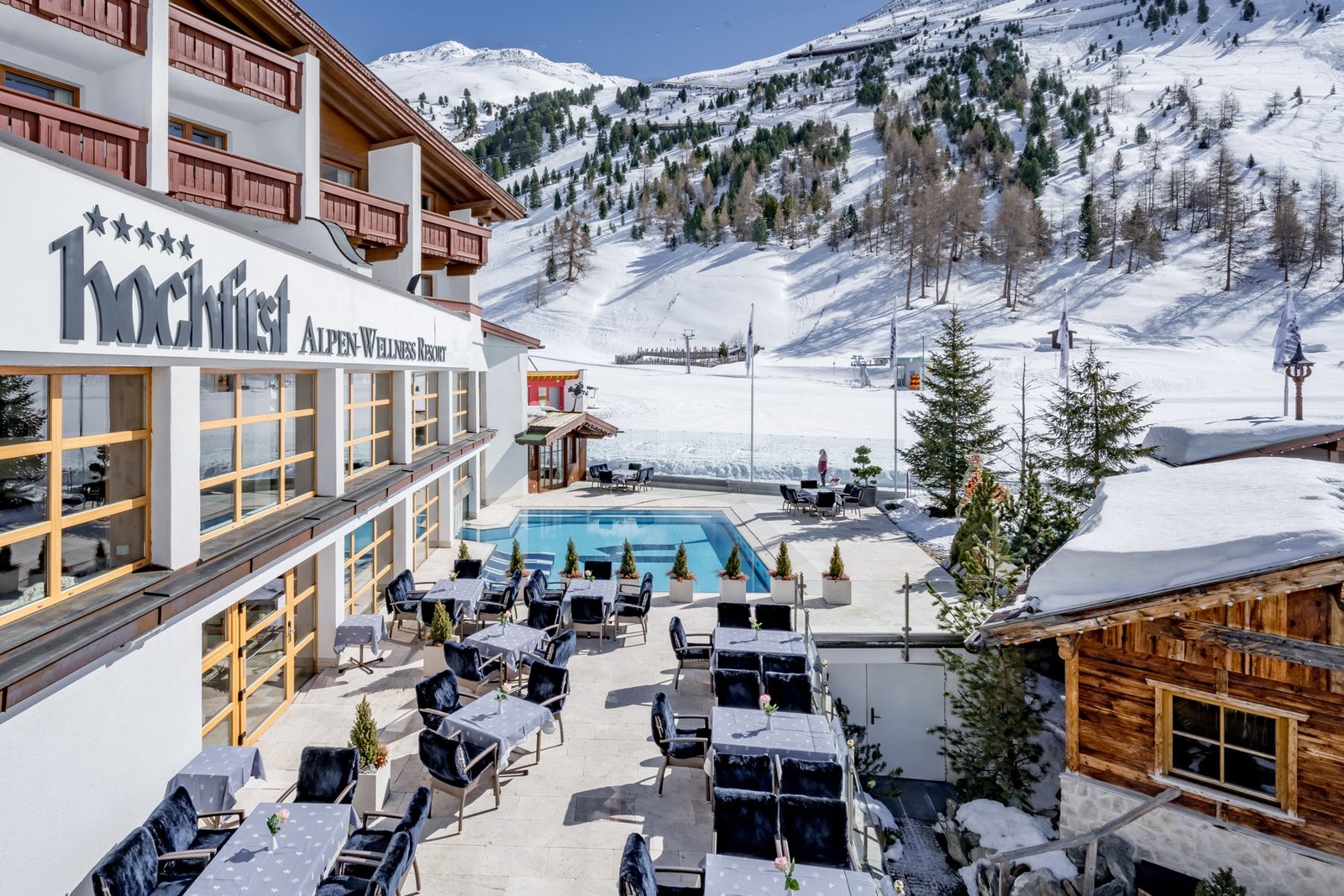 Sonnenterrasse und Outdoorpool des Hochfirst mit direktem Pistenblick.